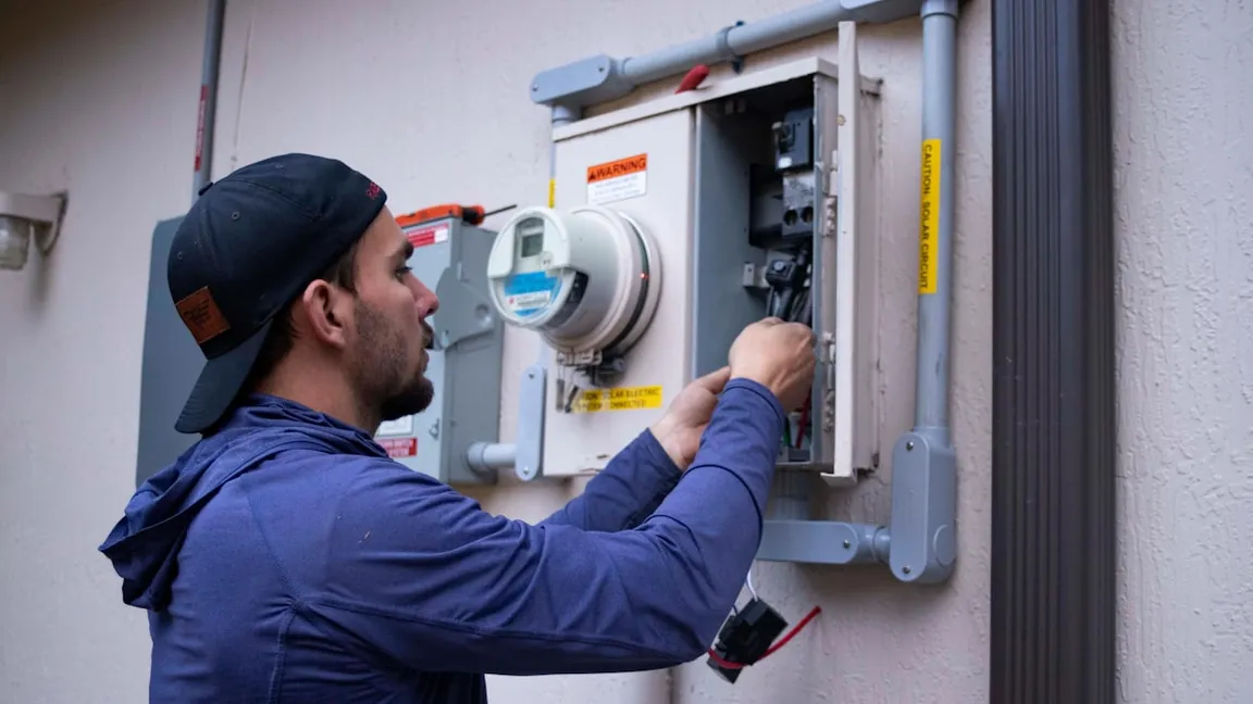 An electrician working in an exterior meter and panel box