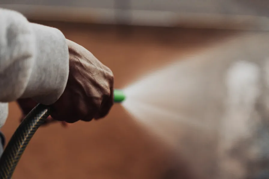 A hand working a sprayer, treatment mist in the air